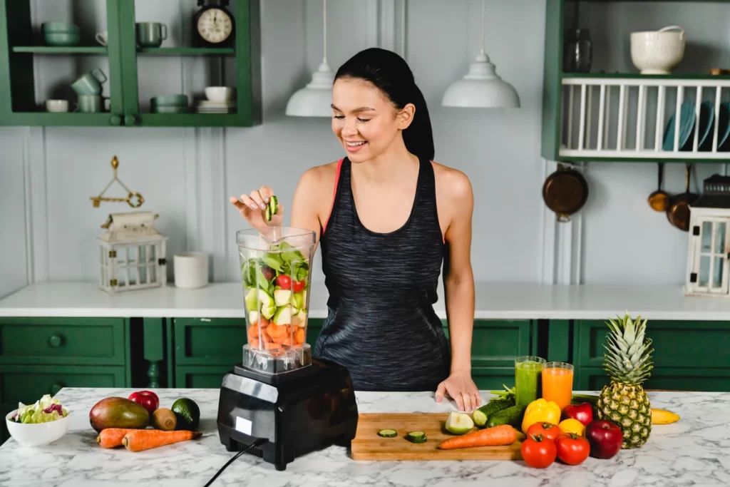 Organic wellness naturals healthy lady woman girl making smoothie blender fruits veggies vegetables leafy greens pineapple carrots peppers cucumber apple banana